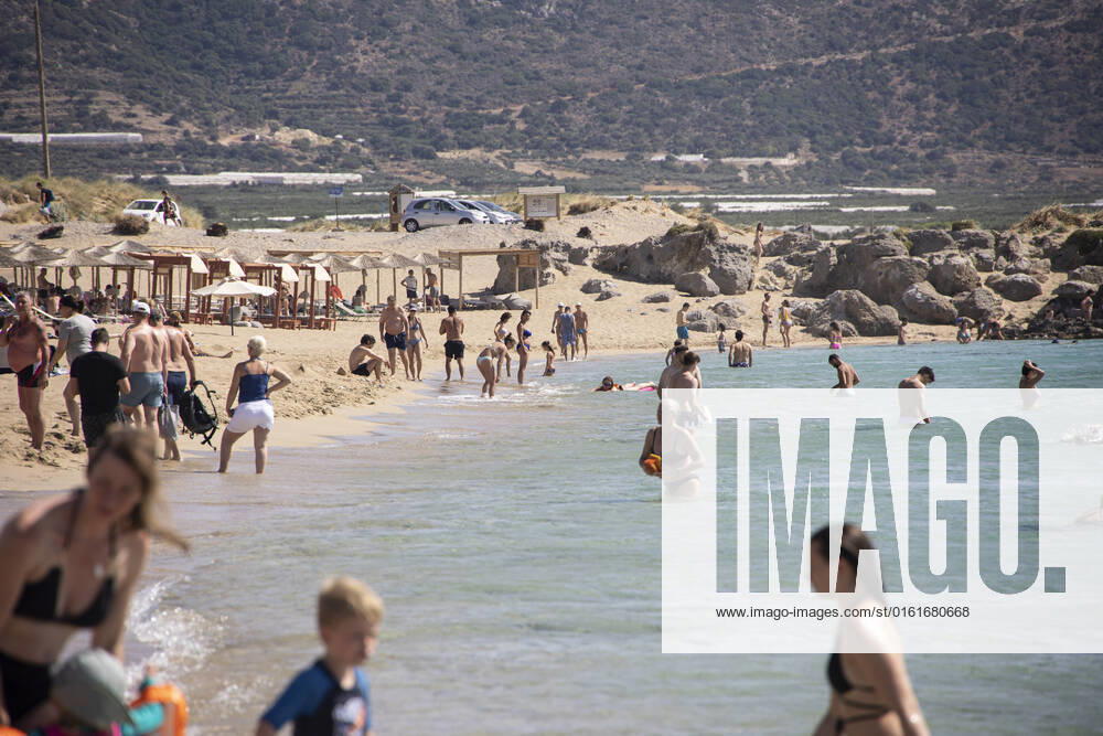 Tourism In Greece - Falassarna Beach In Crete Island Tourism in Greece - The exotic beach of Falassarna at the western side of Crete island. Falasarna bay with 5 beaches with whitish sand and crystal clear transparent tropical turquoise water hosts some of the most famous beaches in Greece, which has been awarded as the best beach of Crete and voted as one of the 10 best beaches in Europe several times in the past. Local people and tourists are seen relaxing, sunbathing, tanning, swimming, doing water sports and walking. Tourism is bouncing back with reservations exceeding the pre-pandemic numbers, putting Greece and the Greek islands on high demand. Tourists travel after the Covid-19 Coronavirus pandemic. Falassarna, Chania, Crete island,
