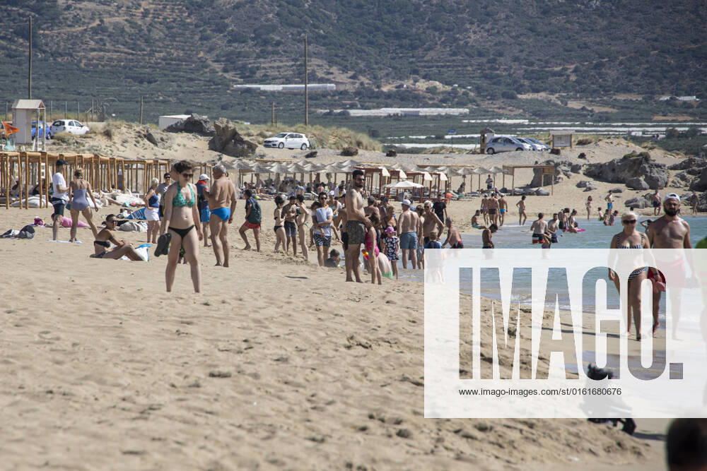Tourism In Greece - Falassarna Beach In Crete Island Tourism in Greece - The exotic beach of Falassarna at the western side of Crete island. Falasarna bay with 5 beaches with whitish sand and crystal clear transparent tropical turquoise water hosts some of the most famous beaches in Greece, which has been awarded as the best beach of Crete and voted as one of the 10 best beaches in Europe several times in the past. Local people and tourists are seen relaxing, sunbathing, tanning, swimming, doing water sports and walking. Tourism is bouncing back with reservations exceeding the pre-pandemic numbers, putting Greece and the Greek islands on high demand. Tourists travel after the Covid-19 Coronavirus pandemic. Falassarna, Chania, Crete island,