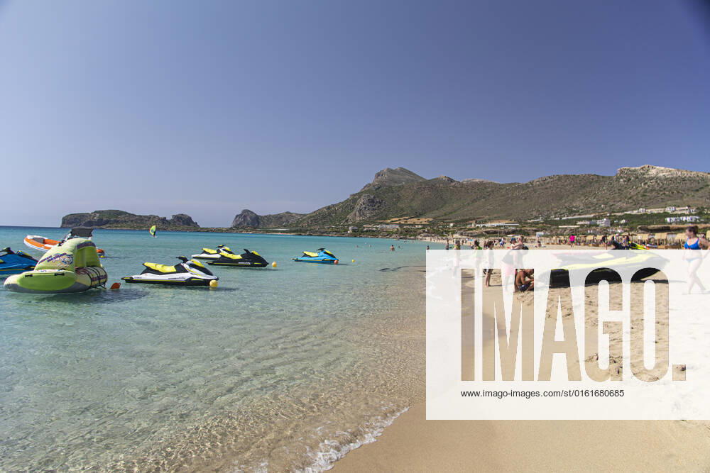 Tourism In Greece - Falassarna Beach In Crete Island Tourism in Greece - The exotic beach of Falassarna at the western side of Crete island. Falasarna bay with 5 beaches with whitish sand and crystal clear transparent tropical turquoise water hosts some of the most famous beaches in Greece, which has been awarded as the best beach of Crete and voted as one of the 10 best beaches in Europe several times in the past. Local people and tourists are seen relaxing, sunbathing, tanning, swimming, doing water sports and walking. Tourism is bouncing back with reservations exceeding the pre-pandemic numbers, putting Greece and the Greek islands on high demand. Tourists travel after the Covid-19 Coronavirus pandemic. Falassarna, Chania, Crete island,