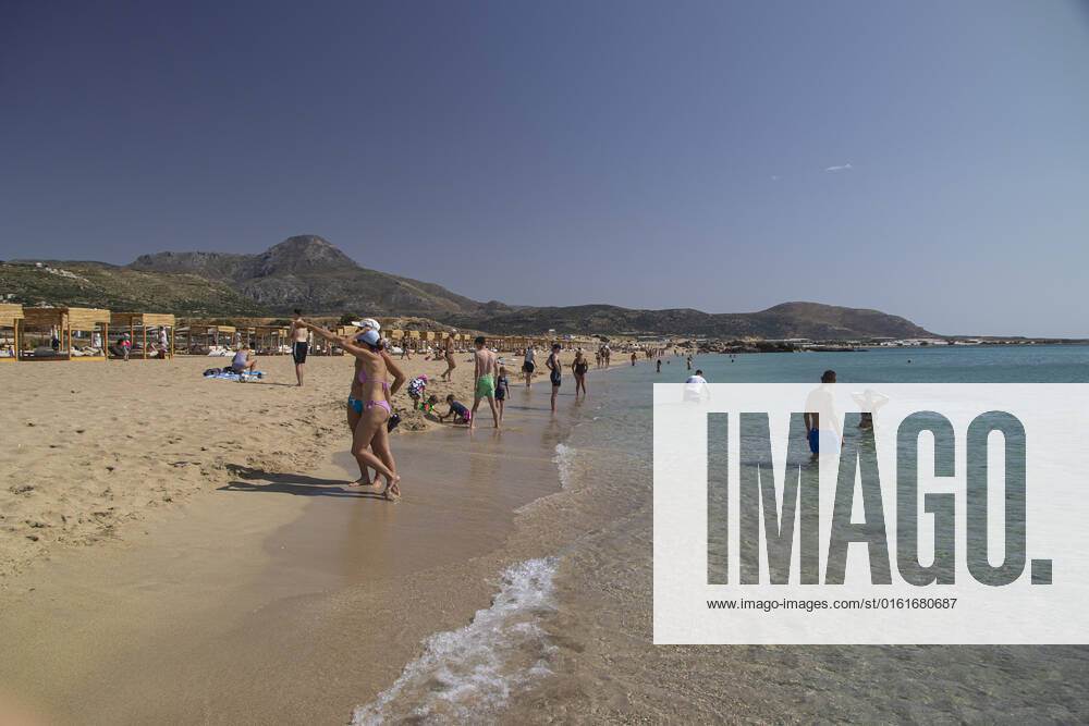 Tourism In Greece - Falassarna Beach In Crete Island Tourism in Greece - The exotic beach of Falassarna at the western side of Crete island. Falasarna bay with 5 beaches with whitish sand and crystal clear transparent tropical turquoise water hosts some of the most famous beaches in Greece, which has been awarded as the best beach of Crete and voted as one of the 10 best beaches in Europe several times in the past. Local people and tourists are seen relaxing, sunbathing, tanning, swimming, doing water sports and walking. Tourism is bouncing back with reservations exceeding the pre-pandemic numbers, putting Greece and the Greek islands on high demand. Tourists travel after the Covid-19 Coronavirus pandemic. Falassarna, Chania, Crete island,