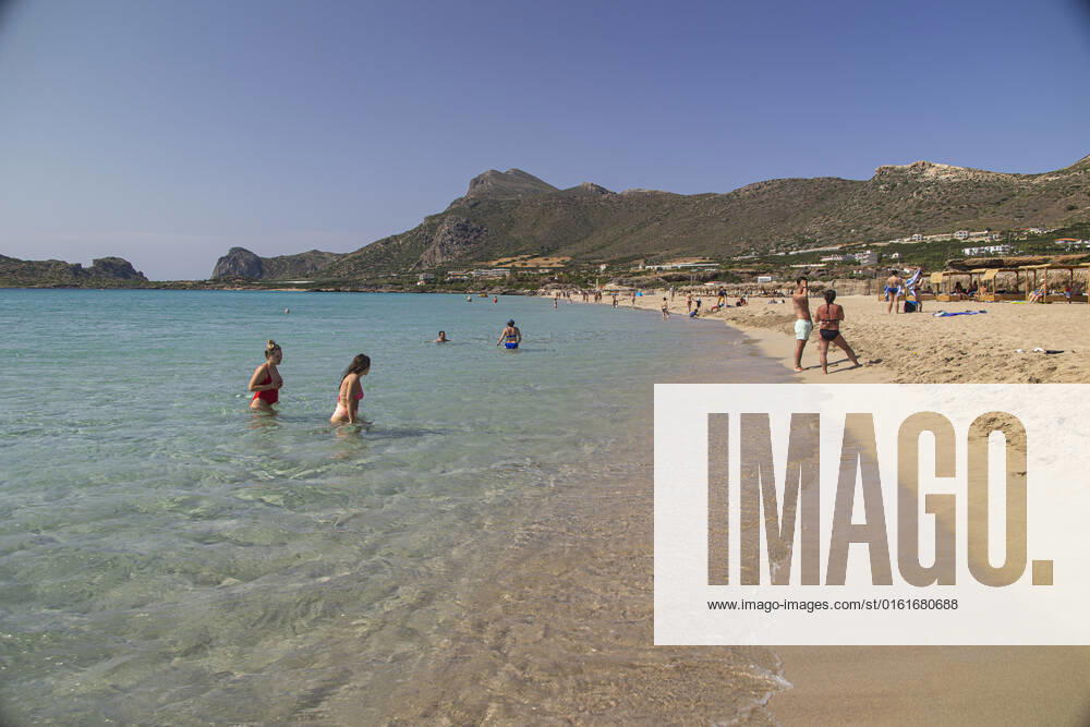 Tourism In Greece - Falassarna Beach In Crete Island Tourism in Greece - The exotic beach of Falassarna at the western side of Crete island. Falasarna bay with 5 beaches with whitish sand and crystal clear transparent tropical turquoise water hosts some of the most famous beaches in Greece, which has been awarded as the best beach of Crete and voted as one of the 10 best beaches in Europe several times in the past. Local people and tourists are seen relaxing, sunbathing, tanning, swimming, doing water sports and walking. Tourism is bouncing back with reservations exceeding the pre-pandemic numbers, putting Greece and the Greek islands on high demand. Tourists travel after the Covid-19 Coronavirus pandemic. Falassarna, Chania, Crete island,