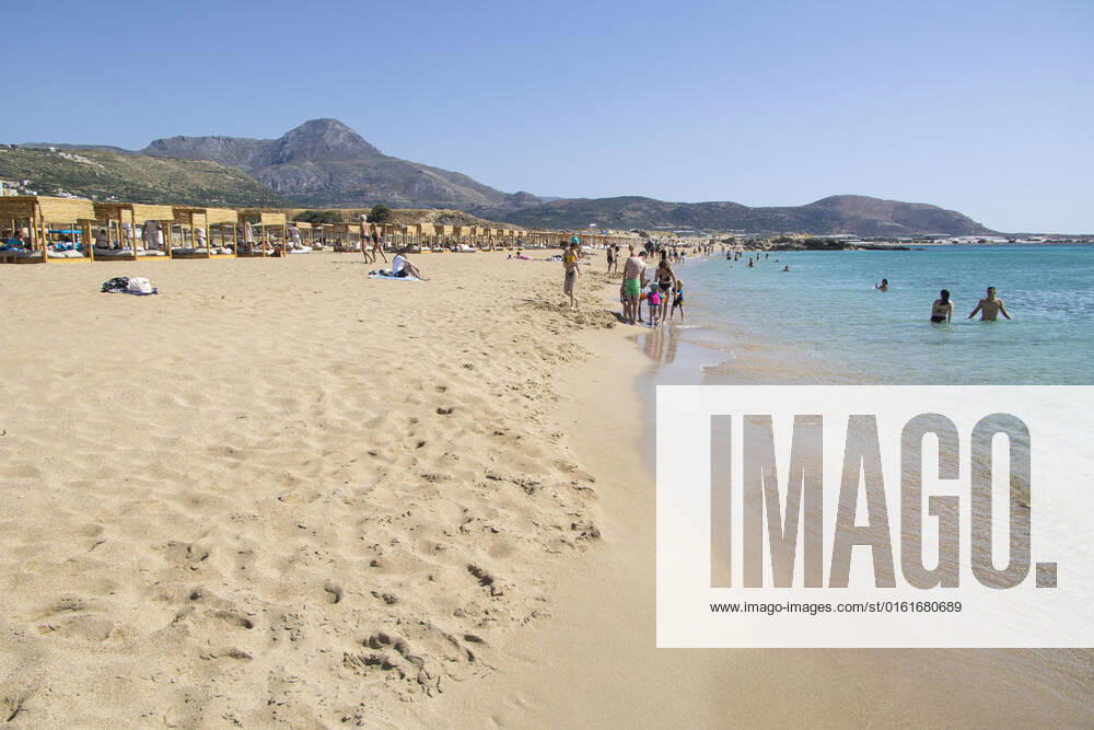 Tourism In Greece - Falassarna Beach In Crete Island Tourism in Greece - The exotic beach of Falassarna at the western side of Crete island. Falasarna bay with 5 beaches with whitish sand and crystal clear transparent tropical turquoise water hosts some of the most famous beaches in Greece, which has been awarded as the best beach of Crete and voted as one of the 10 best beaches in Europe several times in the past. Local people and tourists are seen relaxing, sunbathing, tanning, swimming, doing water sports and walking. Tourism is bouncing back with reservations exceeding the pre-pandemic numbers, putting Greece and the Greek islands on high demand. Tourists travel after the Covid-19 Coronavirus pandemic. Falassarna, Chania, Crete island,