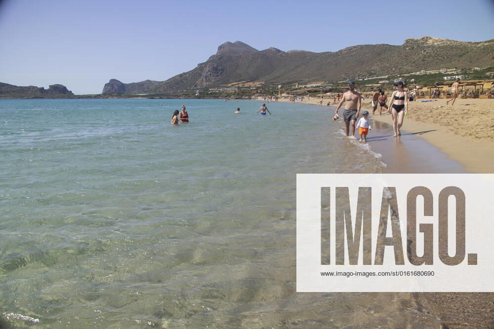 Tourism In Greece - Falassarna Beach In Crete Island Tourism in Greece - The exotic beach of Falassarna at the western side of Crete island. Falasarna bay with 5 beaches with whitish sand and crystal clear transparent tropical turquoise water hosts some of the most famous beaches in Greece, which has been awarded as the best beach of Crete and voted as one of the 10 best beaches in Europe several times in the past. Local people and tourists are seen relaxing, sunbathing, tanning, swimming, doing water sports and walking. Tourism is bouncing back with reservations exceeding the pre-pandemic numbers, putting Greece and the Greek islands on high demand. Tourists travel after the Covid-19 Coronavirus pandemic. Falassarna, Chania, Crete island,