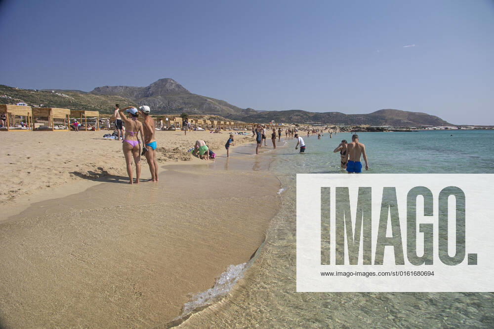 Tourism In Greece - Falassarna Beach In Crete Island Tourism in Greece - The exotic beach of Falassarna at the western side of Crete island. Falasarna bay with 5 beaches with whitish sand and crystal clear transparent tropical turquoise water hosts some of the most famous beaches in Greece, which has been awarded as the best beach of Crete and voted as one of the 10 best beaches in Europe several times in the past. Local people and tourists are seen relaxing, sunbathing, tanning, swimming, doing water sports and walking. Tourism is bouncing back with reservations exceeding the pre-pandemic numbers, putting Greece and the Greek islands on high demand. Tourists travel after the Covid-19 Coronavirus pandemic. Falassarna, Chania, Crete island,