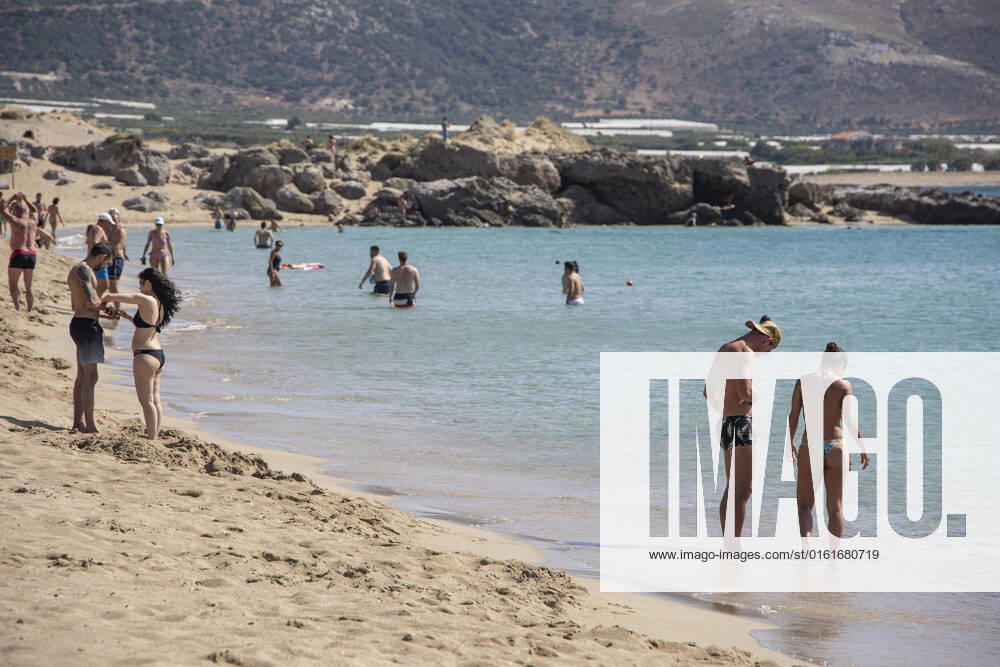 Tourism In Greece - Falassarna Beach In Crete Island Tourism in Greece - The exotic beach of Falassarna at the western side of Crete island. Falasarna bay with 5 beaches with whitish sand and crystal clear transparent tropical turquoise water hosts some of the most famous beaches in Greece, which has been awarded as the best beach of Crete and voted as one of the 10 best beaches in Europe several times in the past. Local people and tourists are seen relaxing, sunbathing, tanning, swimming, doing water sports and walking. Tourism is bouncing back with reservations exceeding the pre-pandemic numbers, putting Greece and the Greek islands on high demand. Tourists travel after the Covid-19 Coronavirus pandemic. Falassarna, Chania, Crete island,