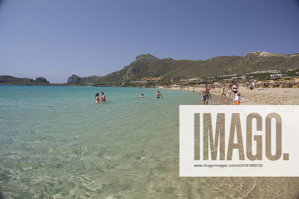 Tourism In Greece - Falassarna Beach In Crete Island Tourism in Greece - The exotic beach of Falassarna at the western side of Crete island. Falasarna bay with 5 beaches with whitish sand and crystal clear transparent tropical turquoise water hosts some of the most famous beaches in Greece, which has been awarded as the best beach of Crete and voted as one of the 10 best beaches in Europe several times in the past. Local people and tourists are seen relaxing, sunbathing, tanning, swimming, doing water sports and walking. Tourism is bouncing back with reservations exceeding the pre-pandemic numbers, putting Greece and the Greek islands on high demand. Tourists travel after the Covid-19 Coronavirus pandemic. Falassarna, Chania, Crete island,