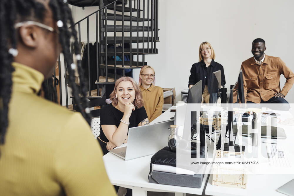 Smiling colleagues looking at businesswoman during meeting in office Sweden, Stockholm, model released, property released