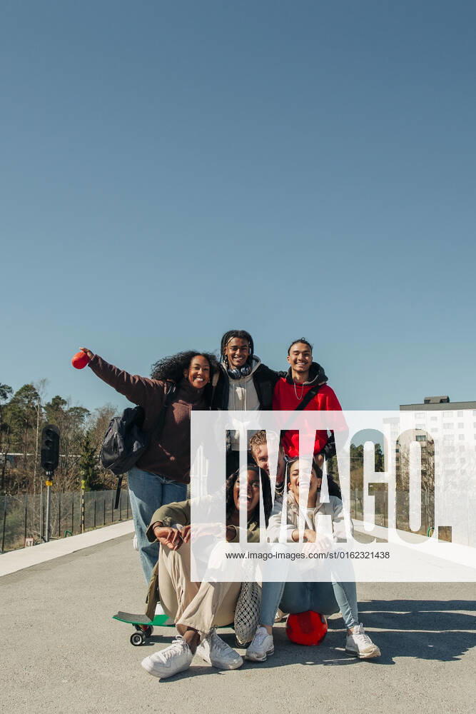 Happy multiracial friends having fun at railroad station platform against clear blue sky on sunny day Sweden, Stockholm, model released