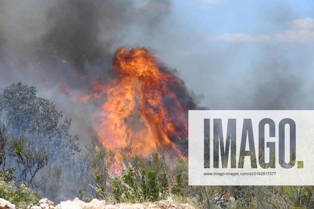 PXL_A fire near Vodice, Croatia Fire in an open area near the Velika Mrdakovica archaeological site in the Vodice hinterland, Croatia on July 13, 2022. About 30 firefighters with a dozen vehicles are on the ground, and two Canadairs joined the ground forces in extinguishing the fire. There are pine forests above, low vegetation, and endangered buildings. HrvojexJelavic PIXSELL