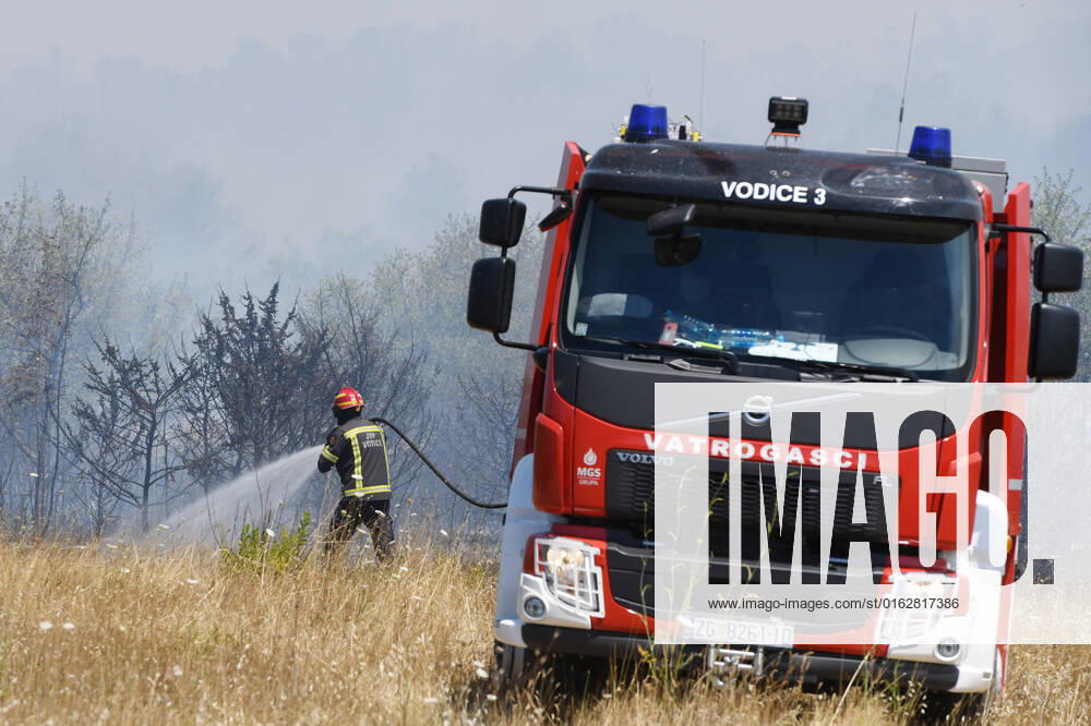 PXL_A fire near Vodice, Croatia Fire in an open area near the Velika Mrdakovica archaeological site in the Vodice hinterland, Croatia on July 13, 2022. About 30 firefighters with a dozen vehicles are on the ground, and two Canadairs joined the ground forces in extinguishing the fire. There are pine forests above, low vegetation, and endangered buildings. HrvojexJelavic PIXSELL