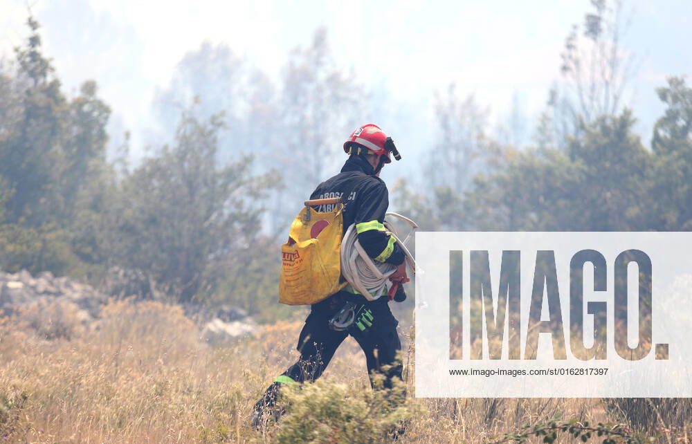 PXL_A fire near Vodice, Croatia Fire in an open area near the Velika Mrdakovica archaeological site in the Vodice hinterland, Croatia on July 13, 2022. About 30 firefighters with a dozen vehicles are on the ground, and two Canadairs joined the ground forces in extinguishing the fire. There are pine forests above, low vegetation, and endangered buildings. DuskoxJaramaz PIXSELL