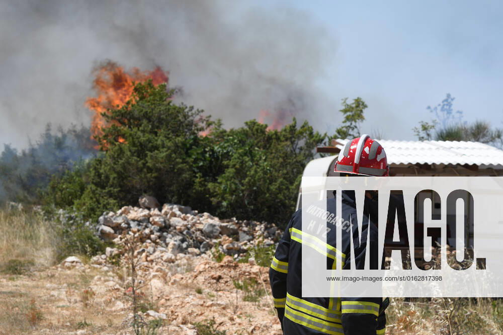 PXL_A fire near Vodice, Croatia Fire in an open area near the Velika Mrdakovica archaeological site in the Vodice hinterland, Croatia on July 13, 2022. About 30 firefighters with a dozen vehicles are on the ground, and two Canadairs joined the ground forces in extinguishing the fire. There are pine forests above, low vegetation, and endangered buildings. HrvojexJelavic PIXSELL