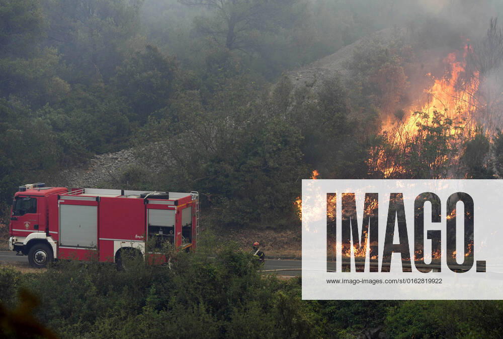 PXL_Zaton fire by the road Fire in an open area near the Zaton site in the Vodice hinterland, Croatia on July 13, 2022. About 30 firefighters with a dozen vehicles are on the ground, and two Canadairs joined the ground forces in extinguishing the fire. There are pine forests above, low vegetation, and endangered buildings. HrvojexJelavic PIXSELL