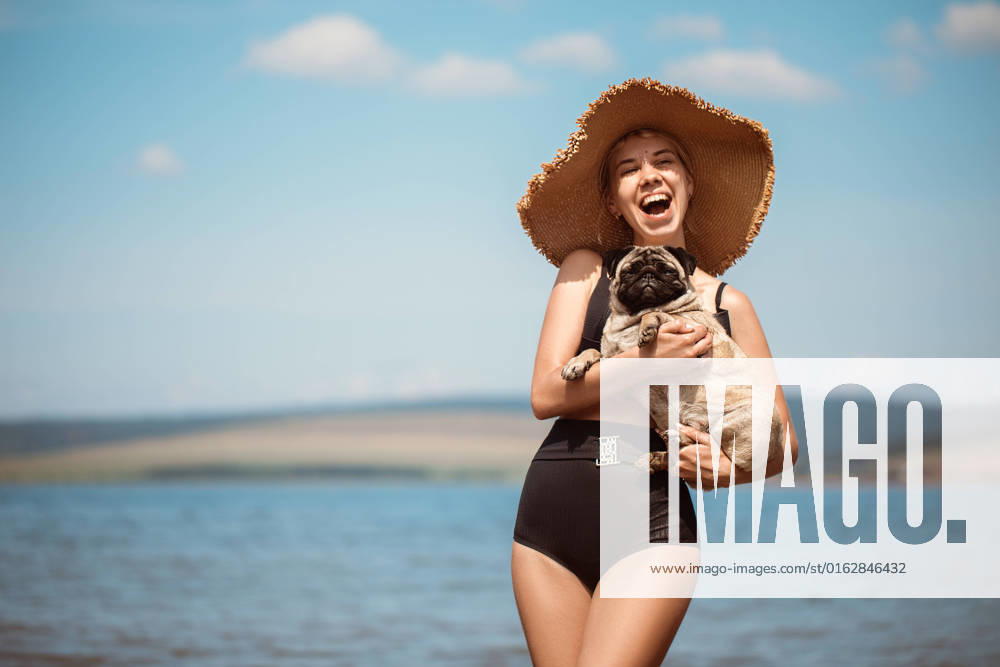 Sexy girl in a wide hat with a pug on the beach Baikal (Port), Irkutsk Oblast, Russia CR_DGAA220713-1009554-01 ,model released, Symbolfoto
