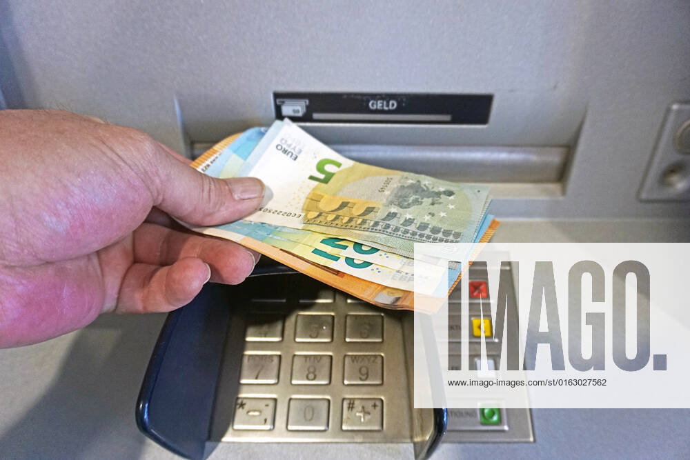Bargeldversorgung aus einem Automat Eine Person holt an einem Geldautomaten Bargeld in 50, 20 und 5 Euro Geldscheinen ab