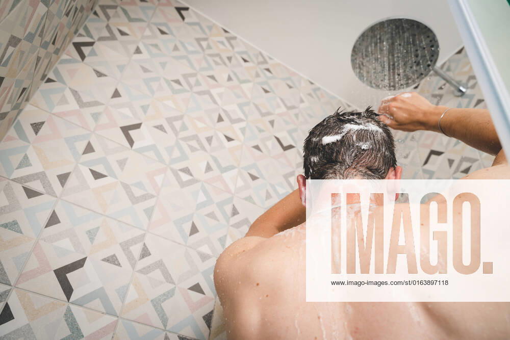 Attraktiver junger Mann duscht sich unter laufendem Wasser in der Dusche im Badezimmer, Körperpflege mit Shampoo