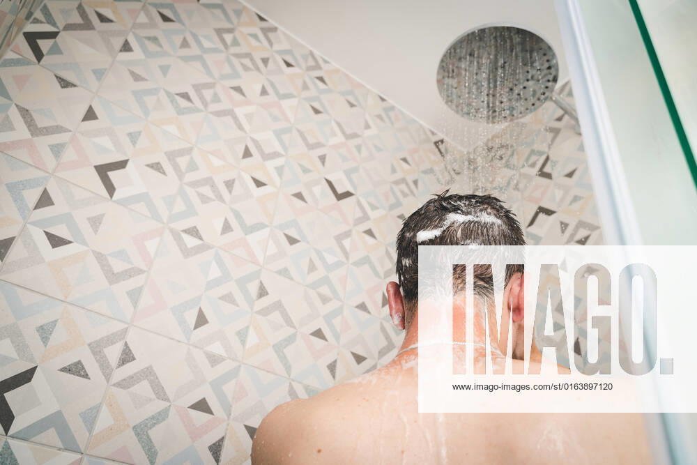 Attraktiver junger Mann duscht sich unter laufendem Wasser in der Dusche im Badezimmer, Körperpflege mit Shampoo