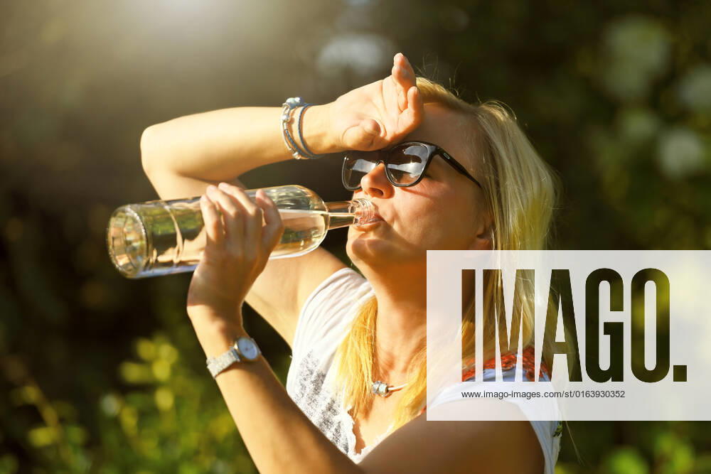 Frau im Garten trinkt Wasser aus einer Flasche, Symbolfoto Hitzewelle
