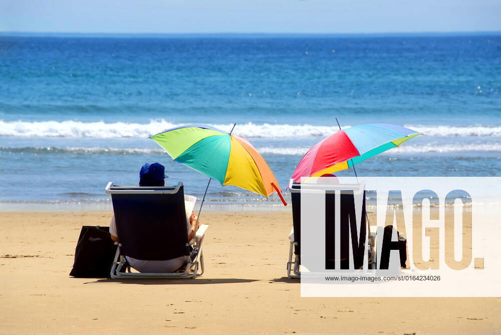 A couple relaxing on a beach under colorful umbrellas