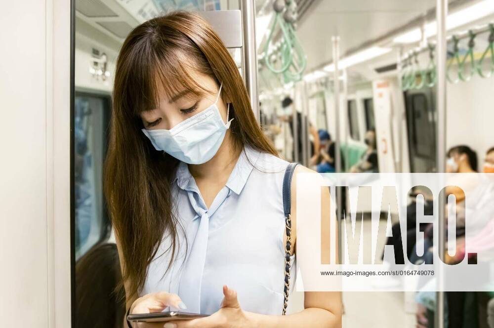 Young Asian woman passenger wearing surgical mask and using mobile phone in subway train, Young Asian woman passenger wearing surgical mask and using mobile phone in subway train model released, Symbolfoto , 06.07.2020 09:52:45,