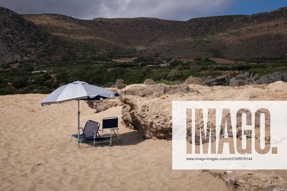 Tourism In Greece - Falassarna Beach In Crete Island An umbrella with two chairs at Falassarna beach near Chania, Crete Island, Greece on August 14, 2022. Falassarna is located 59 kilometers west of Chania. Today is one of the most famous destinations in Crete, for its beaches and for reasons of ecological interest. Falassarna Greece