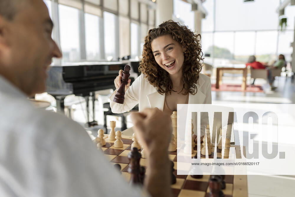 Happy young businesswoman playing chess with mature colleague in office model released, Symbolfoto property released, JCICF00379