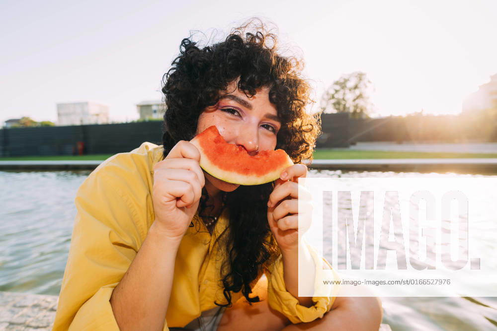 Young woman eating watermelon by pond at sunset model released, Symbolfoto, MEUF07542