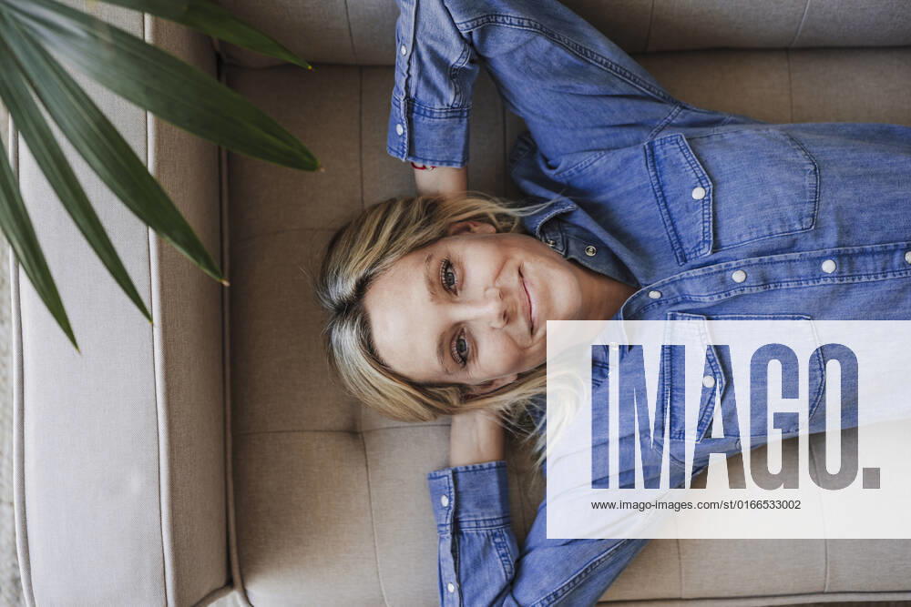 Smiling woman with hands behind head relaxing on sofa model released, Symbolfoto property released, EBBF05820