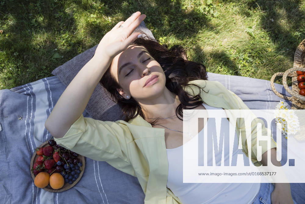 Woman shielding eyes with hand lying at park model released, Symbolfoto, OSF00524