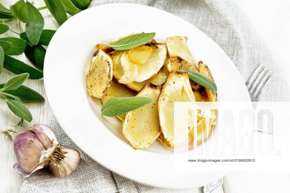 Parsnips baked in plate on white wooden board, Baked parsnips with spices, garlic and sage in a plate on a napkin on wooden board background, Baked parsnips with spices, garlic and sage in a plate on a napkin on wooden board background, 24.05.2021,