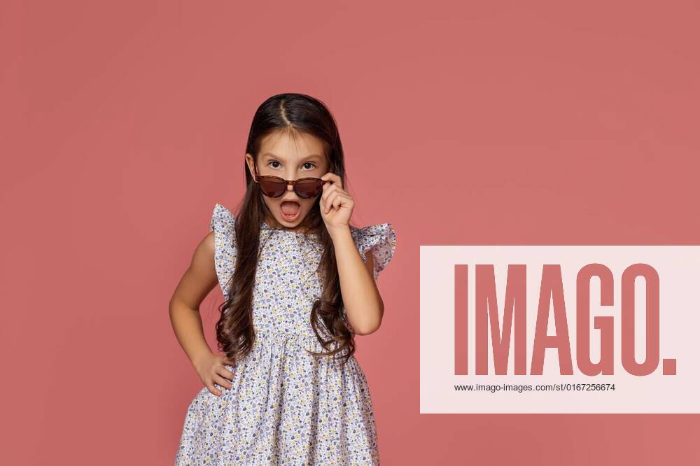 Little child girl in summer dress and sunglasses, surprised little child girl in summer dress and sunglasses looking at the camera on pink background. model released, Symbolfoto , 16.08.2021,