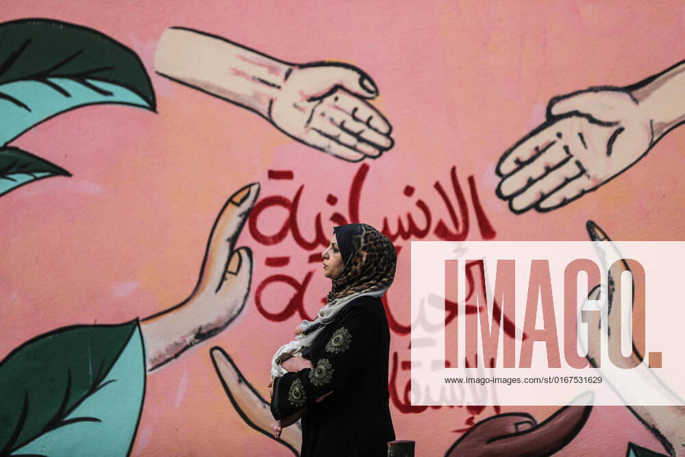 Daily Life In Gaza City A Palestinian woman carrying her child walks in front of a mural at al-Shati camp for Palestinian refugees in Gaza City, on August 29, 2022. Gaza Palestine