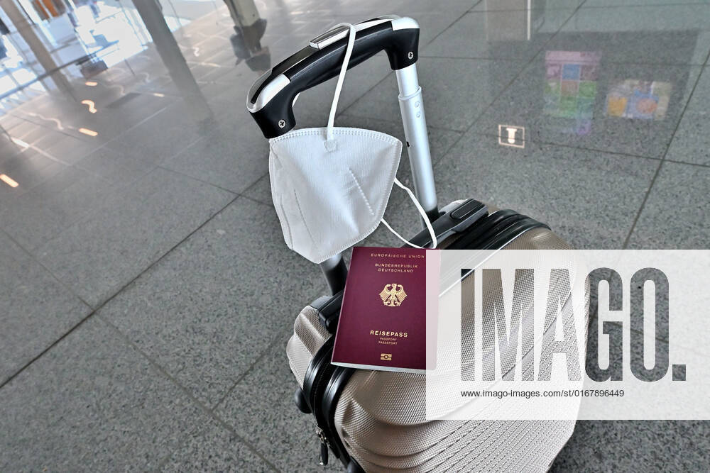 Auf dem Koffer am Flughafen, liegen Reisepass und Mundschutz griffbereit. Im Flugzeug bleibt die Maskenpflicht. München Bayern Deutschland