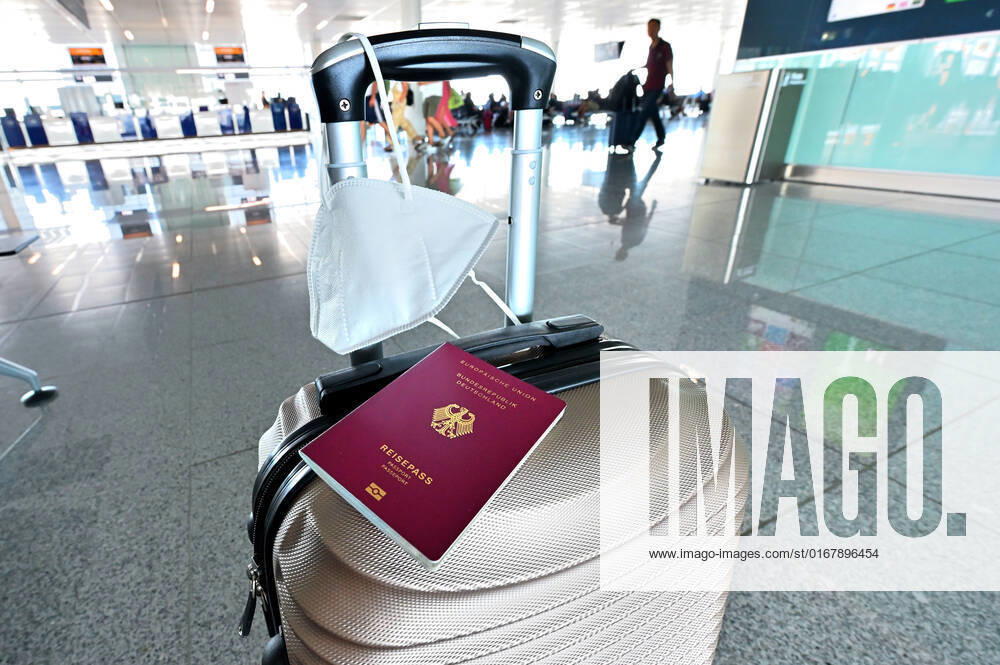 Auf dem Koffer am Flughafen, liegen Reisepass und Mundschutz griffbereit. Im Flugzeug bleibt die Maskenpflicht. München Bayern Deutschland