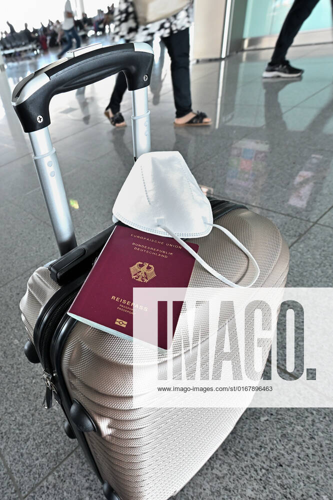 Auf dem Koffer am Flughafen, liegen Reisepass und Mundschutz griffbereit. Im Flugzeug bleibt die Maskenpflicht. München Bayern Deutschland