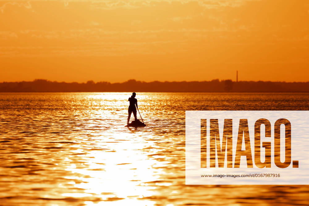 IMAGO Creative: 2022 Sport Favoriten IMAGO Creative: Business - Work-Life Balance girl on SUP Board in golden sunset silhouette of a teenage girl on a Stand Up Paddle Board SUP. Golden sunset sky reflecting in the water. Greifswalder Bodden, Baltic Sea