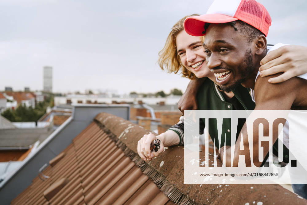 IMAGO Kreativ: Urbane Kultur - Sommer auf den Dächern Male friends laughing while enjoying on rooftop Germany, Berlin, model released, property released
