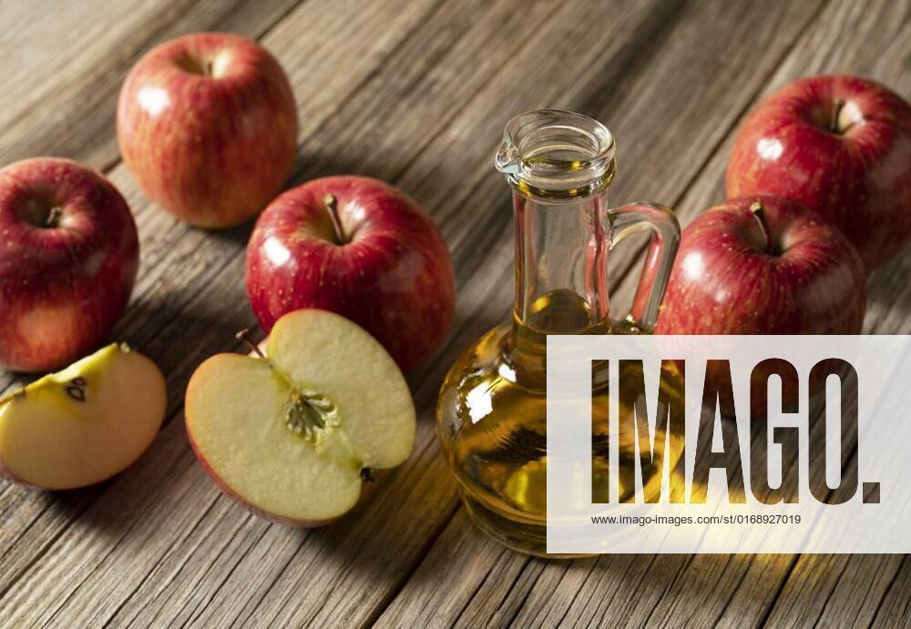 Apple vinegar in a glass container against a wooden background, Apple vinegar in a glass container against a wooden background with lots of apples around it., Apple vinegar in a glass container against a wooden background with lots of apples around it., 10.12.2021,