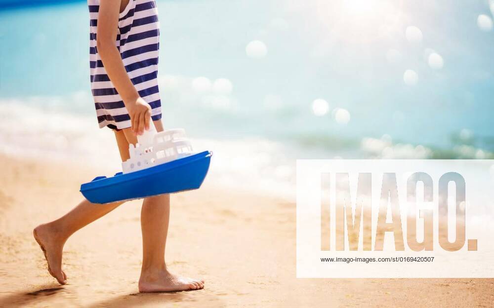 Little boy playing on the sea beach with toy ship, Little boy playing on the sea beach with toy ship. Concept of childhood and family vacation., Little boy playing on the sea beach with toy ship. Concept of childhood and family vacation. model released, Symbolfoto , 13.05.2022,