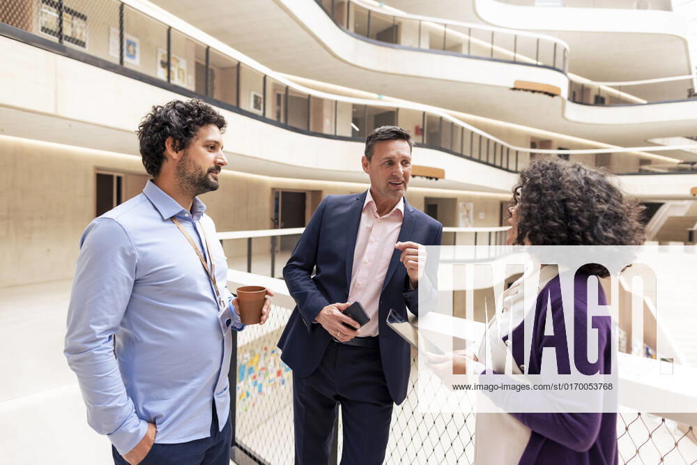 Smiling businessman planning strategy with colleagues in office corridor model released, Symbolfoto property released, JOSEF12674