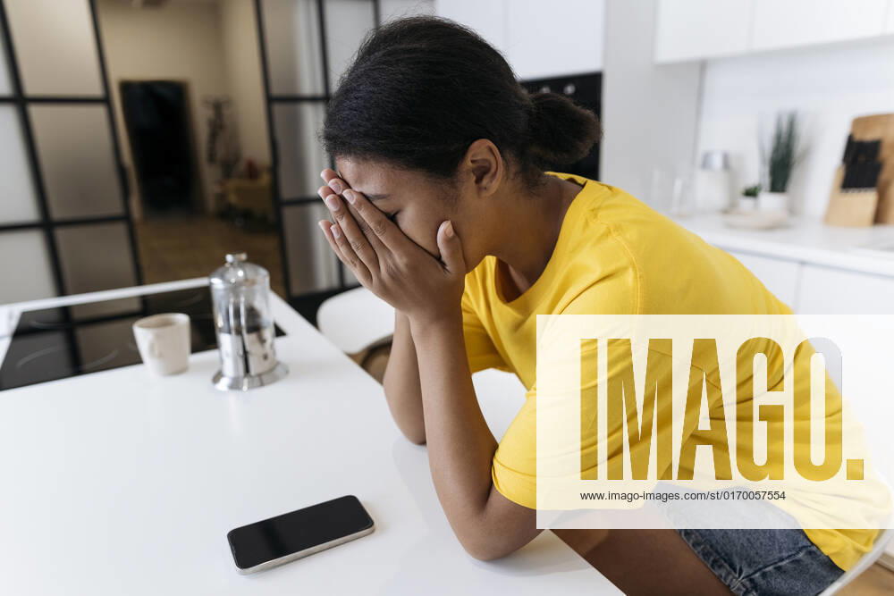 Unhappy woman sitting at the table in the kitchen with head in hands model released, Symbolfoto property released, SIF00473