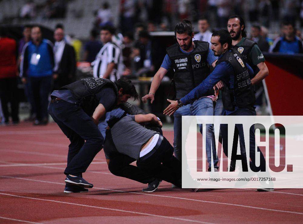 UEFA Champions League playoff first leg match match between Besiktas and Arsenal at Olympic stadium in istanbul 19 august 2014. Score: Besiktas 0 - Arsenal 0 Pictured: Turkish police officer checks a fan of Besiktas who jumped onto the field during the UEFA Champions League play-off first leg football match Besiktas vs Arsenal at the Ataturk Olympic Stadium in Istanbul, on August 19, 2014.