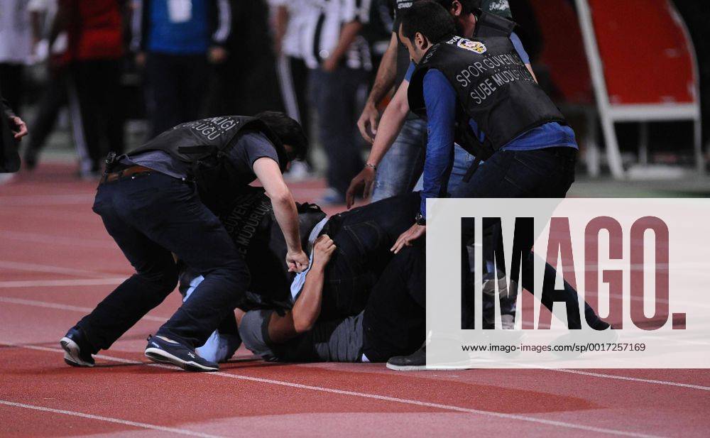UEFA Champions League playoff first leg match match between Besiktas and Arsenal at Olympic stadium in istanbul 19 august 2014. Score: Besiktas 0 - Arsenal 0 Pictured: Turkish police officer checks a fan of Besiktas who jumped onto the field during the UEFA Champions League play-off first leg football match Besiktas vs Arsenal at the Ataturk Olympic Stadium in Istanbul, on August 19, 2014.