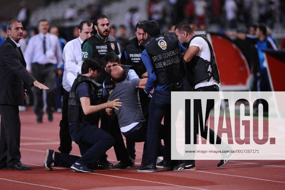 UEFA Champions League playoff first leg match match between Besiktas and Arsenal at Olympic stadium in istanbul 19 august 2014. Score: Besiktas 0 - Arsenal 0 Pictured: Turkish police officer checks a fan of Besiktas who jumped onto the field during the UEFA Champions League play-off first leg football match Besiktas vs Arsenal at the Ataturk Olympic Stadium in Istanbul, on August 19, 2014.