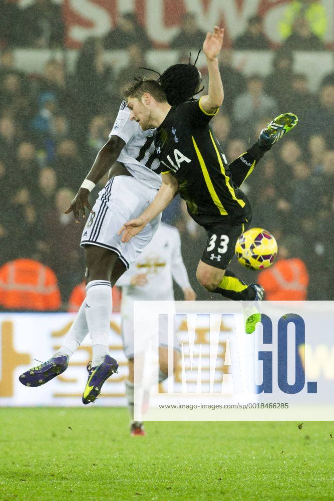 Football - 2014 2015 Premier League - Swansea City vs. Tottenham Hotspur Bafétimbi Gomis of Swansea & Ben Davies Tottenham of Hotspurs collide in the air at The Liberty Stadium. COLORSPORT WINSTON BYNORTH