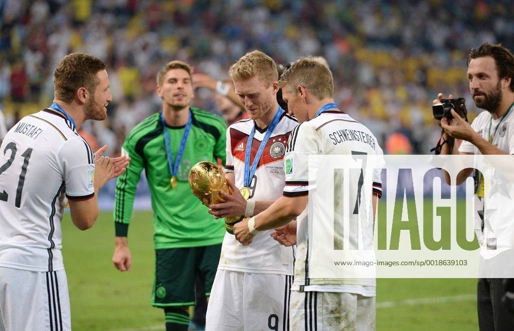 FUSSBALL WM 2014 FINALE Deutschland - Argentinien 13.07.2014 DEUTSCHLAND FEIERT DEN WM TITEL 2014: Andre Schürrle (Mitte li) und Bastian Schweinsteiger (Mitte re) WM Pokal fotografiert von Paul Ripke (re) beobachtet von Shkodran Mustafi (li)