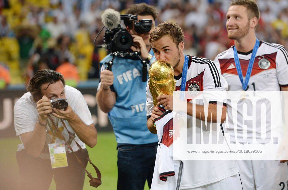 FUSSBALL WM 2014 FINALE Deutschland - Argentinien 13.07.2014 DEUTSCHLAND FEIERT DEN WM TITEL 2014: Matchwinner, Torschütze zum 1-0 Sieg, Mario Götze (Mitte) küsst den WM Pokal fotografiert von Paul Ripke (li); Shkodran Mustafi (re hinten)