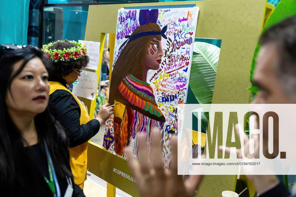 Participants talk as a woman paints a portrait of indigenous person during the COP27 UN Climate Change Conference, held by UNFCCC in Sharm El-Sheikh International Convention Center. COP27, running from November 6 to November 18 in Sharm El Sheikh focuses on implementation of measures already agreed during previous COPs. The Conference in Sharm El Sheikh focuses also on the most vulnerable communities as the climate crisis hardens life conditions of those already most disadvantaged. Sharm El Sheikh Egypt - ZUMAs197 20221116_zaa_s197_262