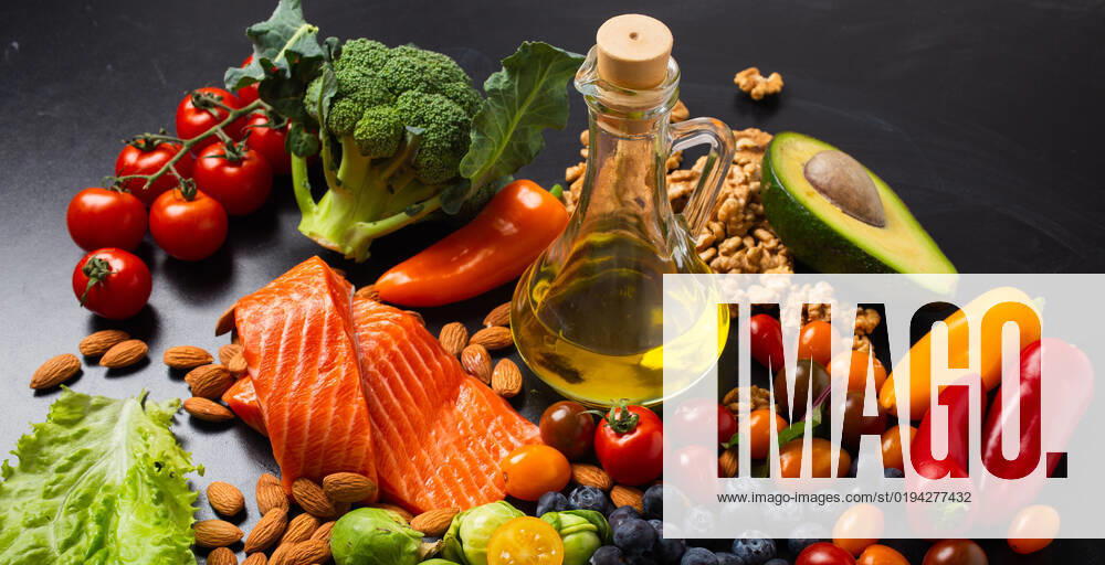 Healthy diet and nutrition food rich in vitamins and omega-3 concept Healthy diet and nutrition food rich in vitamins and omega-3 concept, assorted fresh vegetables, green salad, fruit, fish salmon, nuts, blueberries, bottle of olive oil on black chalk board background
