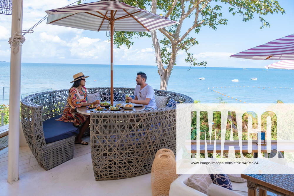 Couple having lunch at an restaurant looking out over the ocean of Pattaya Thailand, man and woman having dinner in restaurant by the ocean in Pattaya couple having lunch at a restaurant looking out over the ocean of Pattaya Thailand, man and woman having dinner in a restaurant by the ocean in Pattaya.